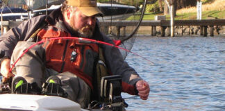 kayak angler Brad Hole lifts a cutthroat trout from the waters of Lake Washington in winter