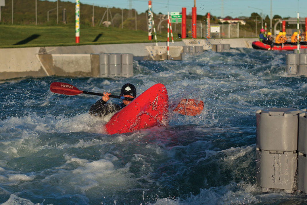 a kayaker plays in whitewater at Vector Wero Whitewater Park in Auckland, home to to the world's first raftable artificial waterfall