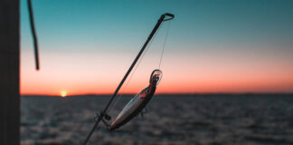a fishing rod with lure in front of a sunset when the fishing trip is over