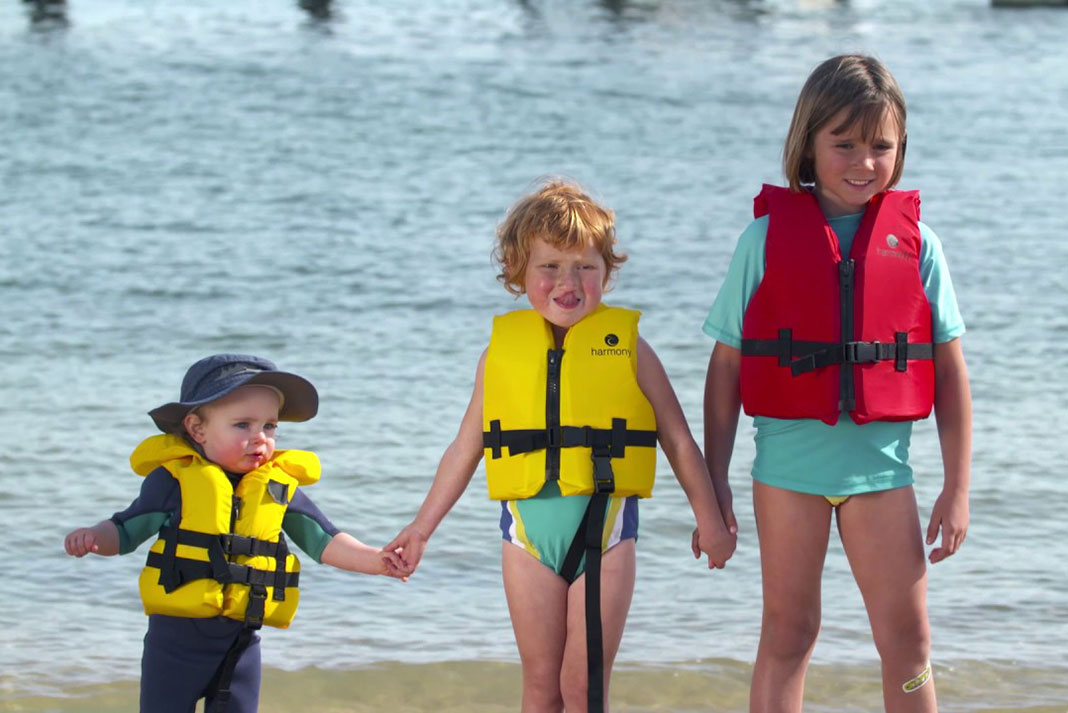 Three children wearing different lifejackets fitted according to weight.