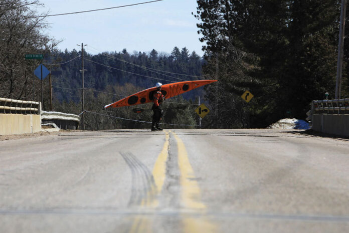 a kayaker carries a kayak across the road