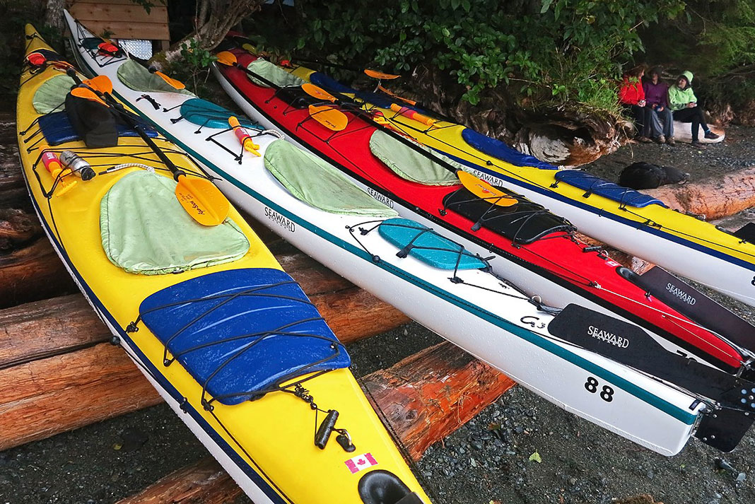 touring kayaks on a beach with hatches protected from a rainy weather forecast