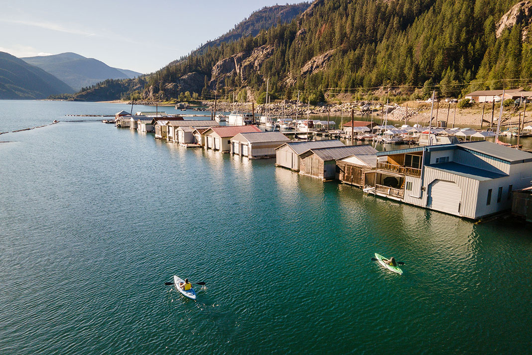 two people kayaking past wharfs and boat houses near Castlegar, British Columbia
