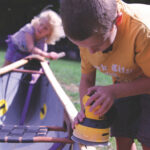 Tough Love: Teaching Skills To The Next Generation Of Canoeists a boy and girl working on a canoe