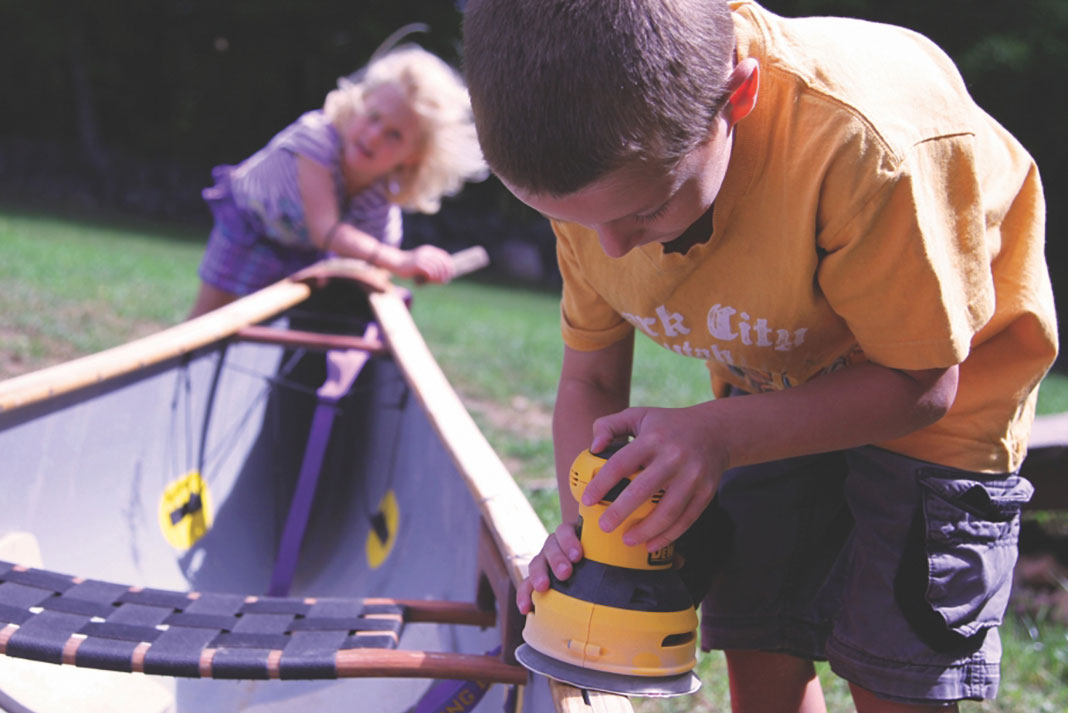 a boy and girl working on a canoe