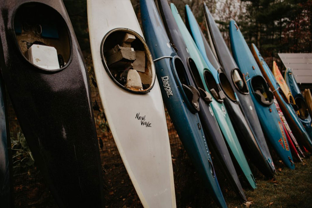 a number of C1 boats are arranged in a row in Adam Pearsall’s backyard canoe museum