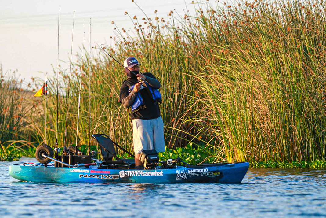 kayak angler stands up and reels while fishing the California Delta
