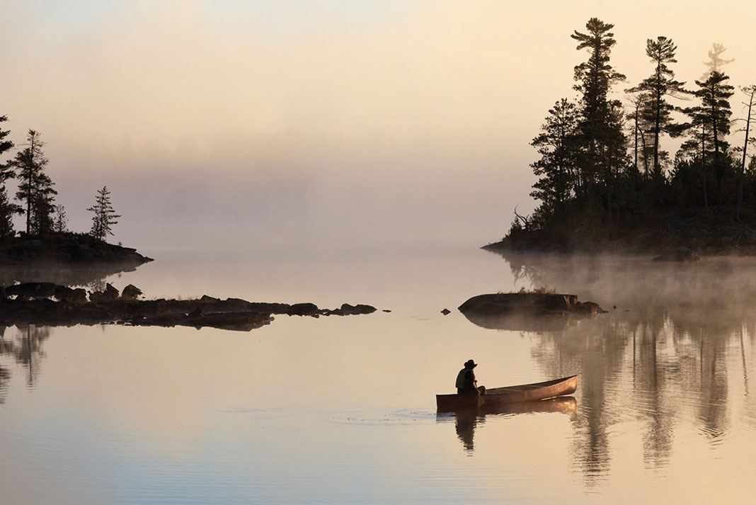 a canoeist paddles on misty water