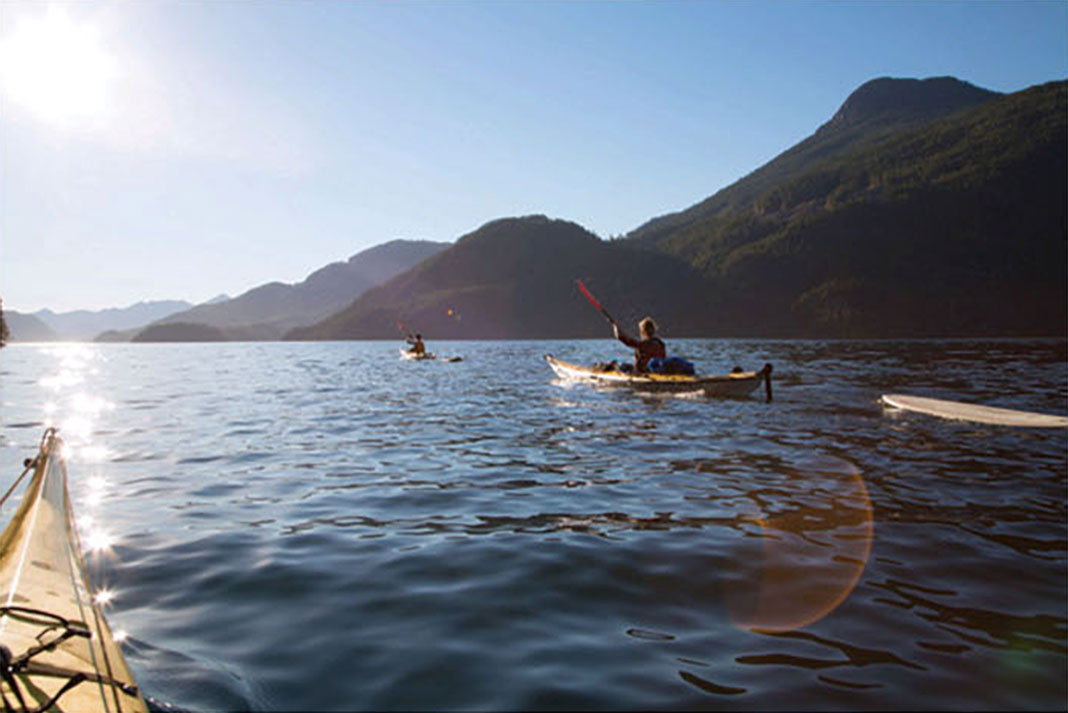 four sea kayaker set out for Kyuquot Sound towing surfboards