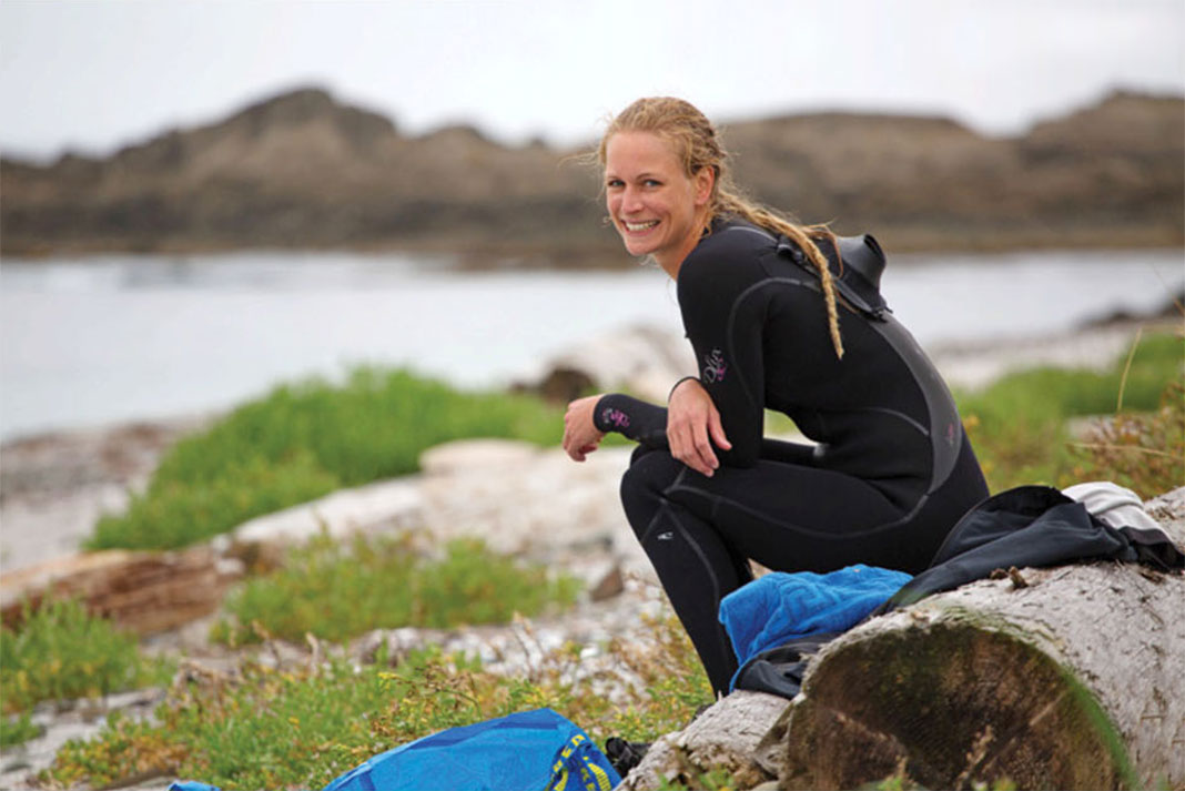woman in wetsuit smiles while taking a break from surfing on Vancouver Island