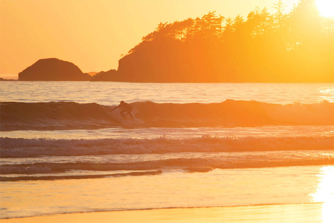 person surfing at sunset on Vancouver Island's Kyuquot Sound