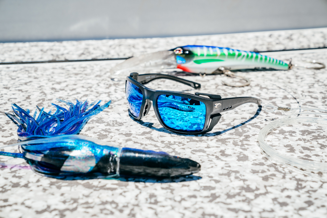 Sunglasses and fishing lures on flat surface.