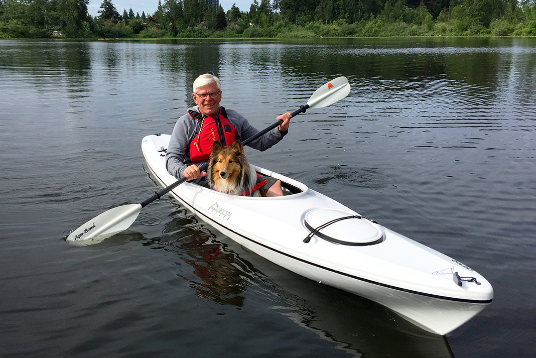 man paddles a kayak with his dog