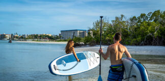 man and woman carry Boardworks inflatable paddleboards into the water