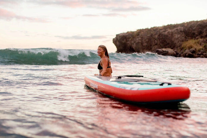 woman stands in surf with a Boardworks inflatable paddleboard