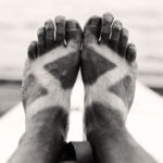 a paddler's deeply suntanned feet in black and white