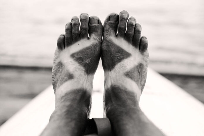a paddler's deeply suntanned feet in black and white