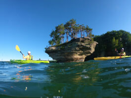 two people paddle Evoke kayaks past a flowerpot island