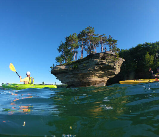 two people paddle Evoke kayaks past a flowerpot island