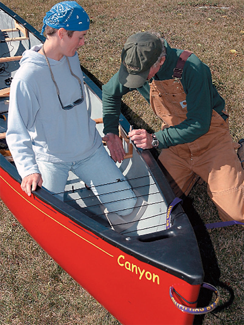 man and woman size a whitewater tripping canoe for kneepads and thigh straps