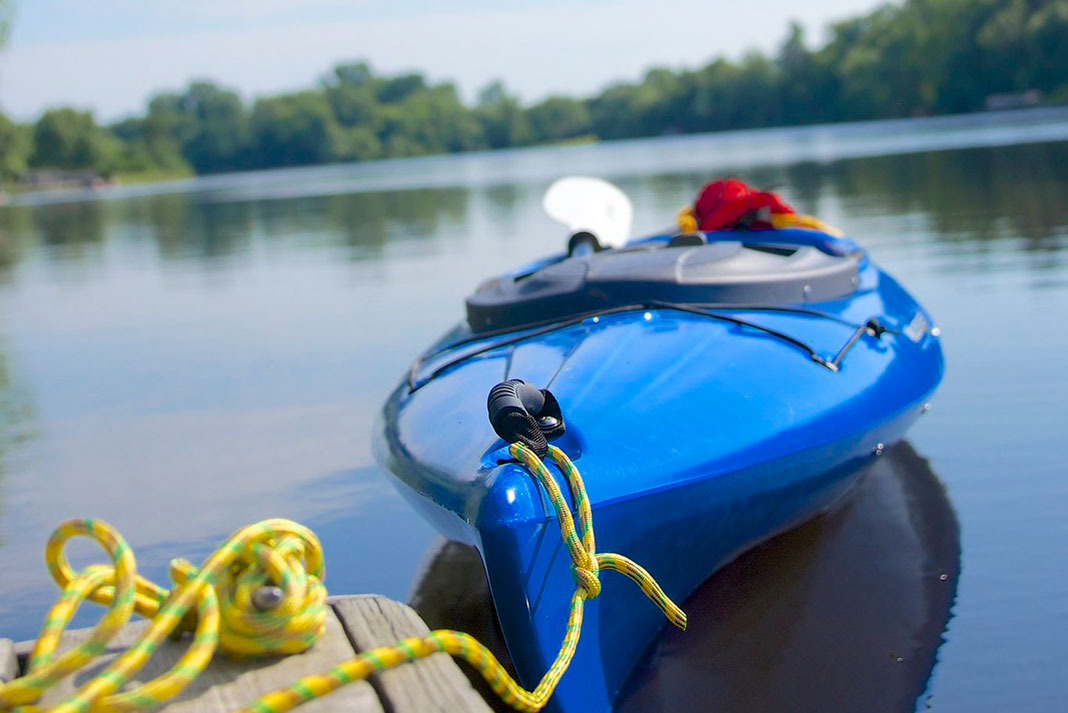 a blue kayak tied up to a dock with yellow rope