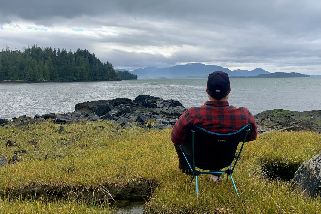 Man sitting in a Helinox Chair One looking out at the water.