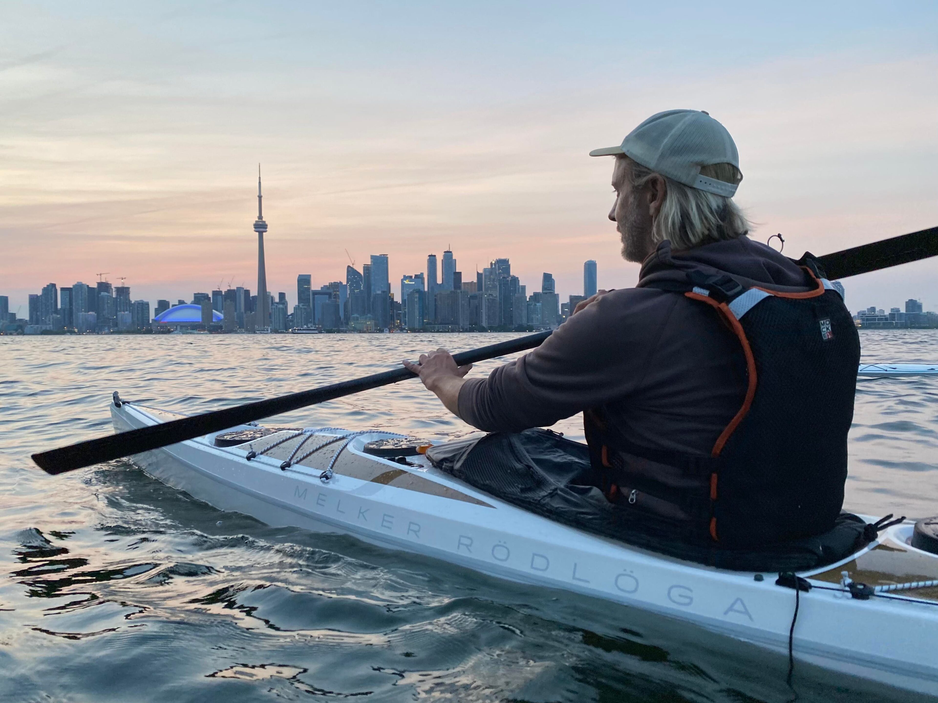 Person paddling Melker Rodloga sea kayak with Toronto skyline in background.