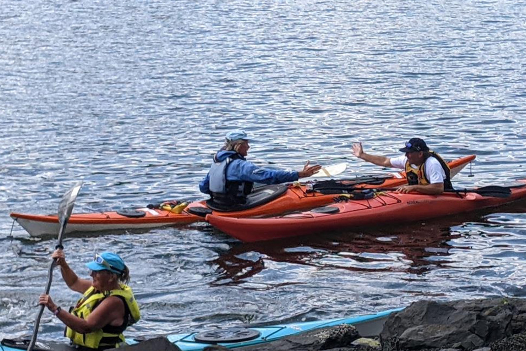 Mark extends hand to fellow kayaker for a high five
