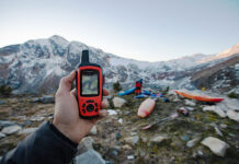 person holds up a Garmin handheld GPS at a mountainous kayak location