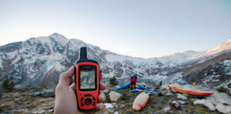 person holds up a Garmin handheld GPS at a mountainous kayak location