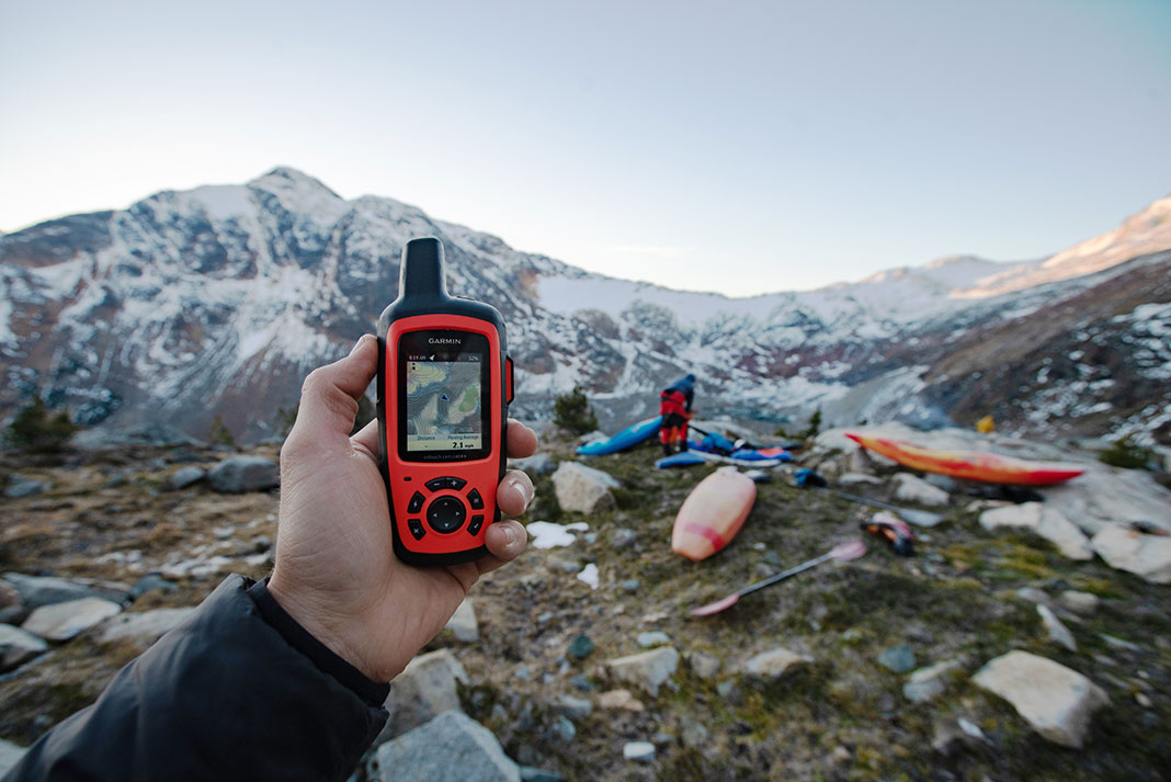 Persona que sostiene un dispositivo GPS portátil Garmin en un sitio de montaña para practicar kayak