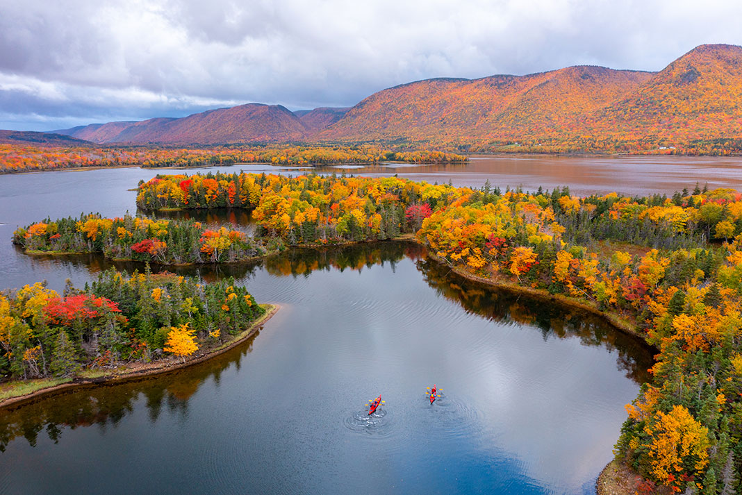 two touring kayakers paddle through a picturesque lake in fall