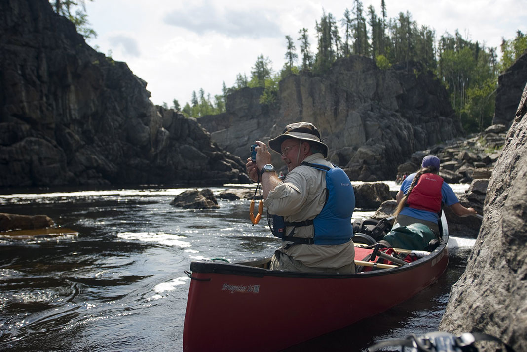 man stops and takes a photo while canoeing the Missinaibi River