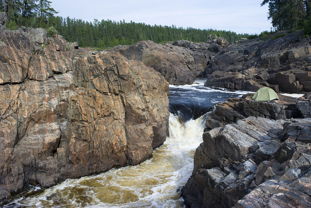 a tent pitched beside large waterfall along the Missinaibi River