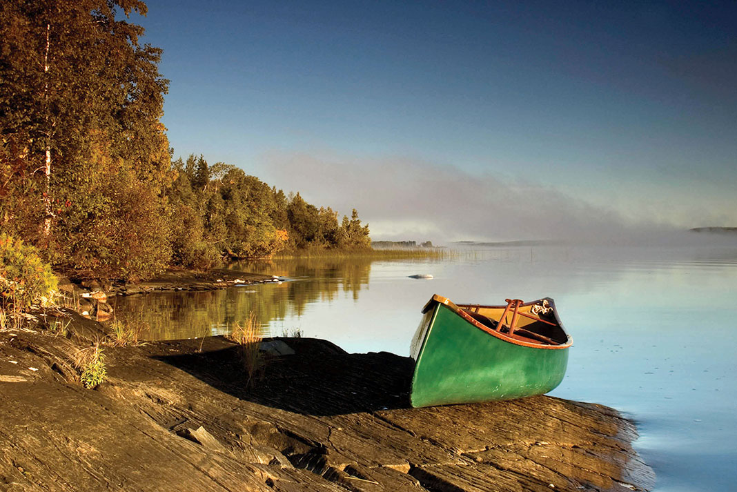 a Prospector canoe rests on the shore of a lake