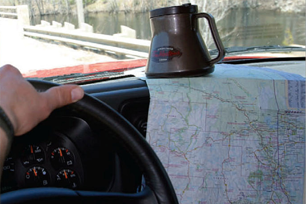Person drives truck with coffee pot and map on dash