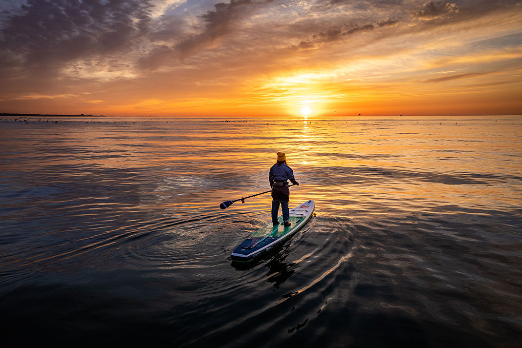 a person standup paddleboarding in the morning
