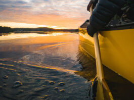 person paddling a yellow canoe at sunset