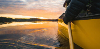 person paddling a yellow canoe at sunset