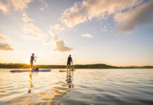 two people paddling on hard paddleboards at dawn