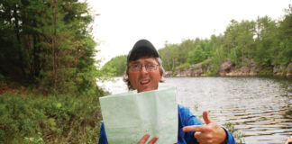 man holds up map in front of river after getting lost