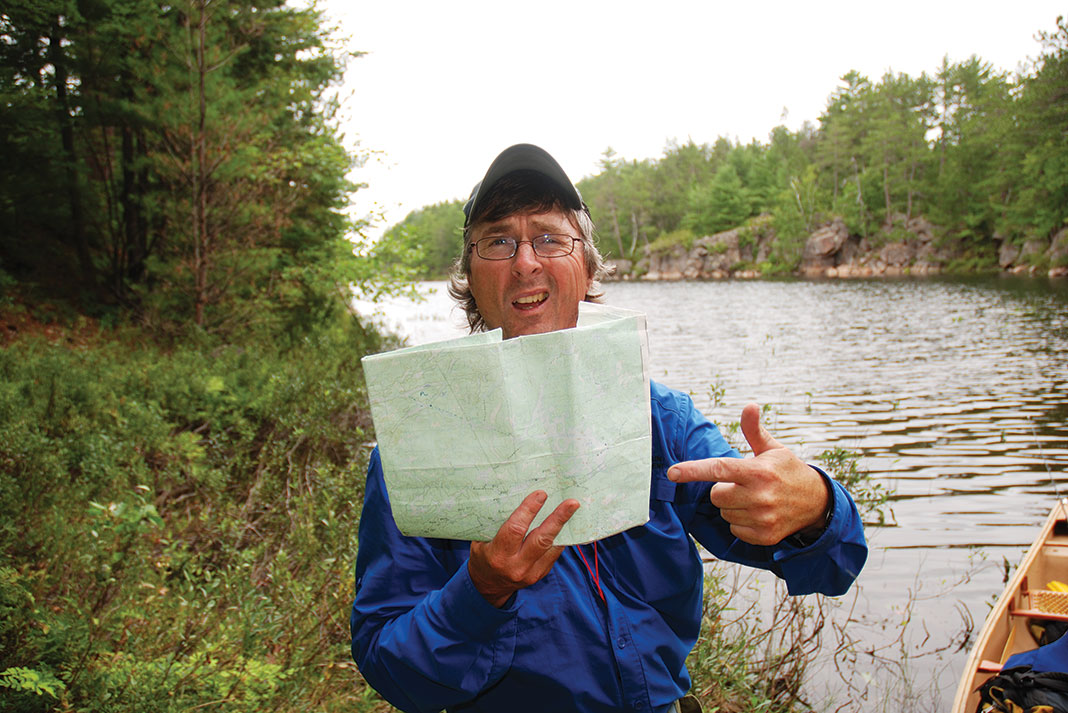 man holds up map in front of river after getting lost