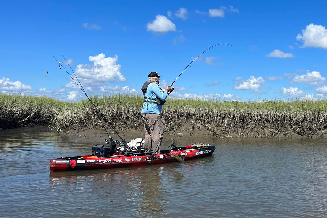 Man stands and fishes for backwater redfish from his kayak