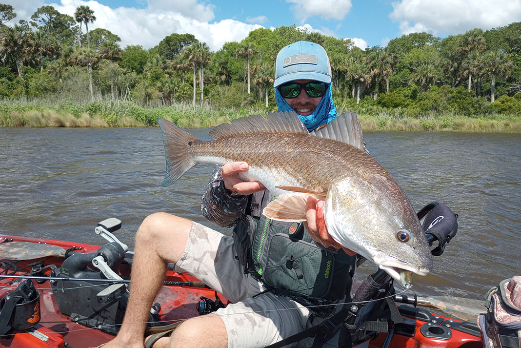 man holds redfish caught from a fishing kayak in Florida