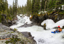 a whitewater paddler looks downriver during the spring runoff before running the scary rapids