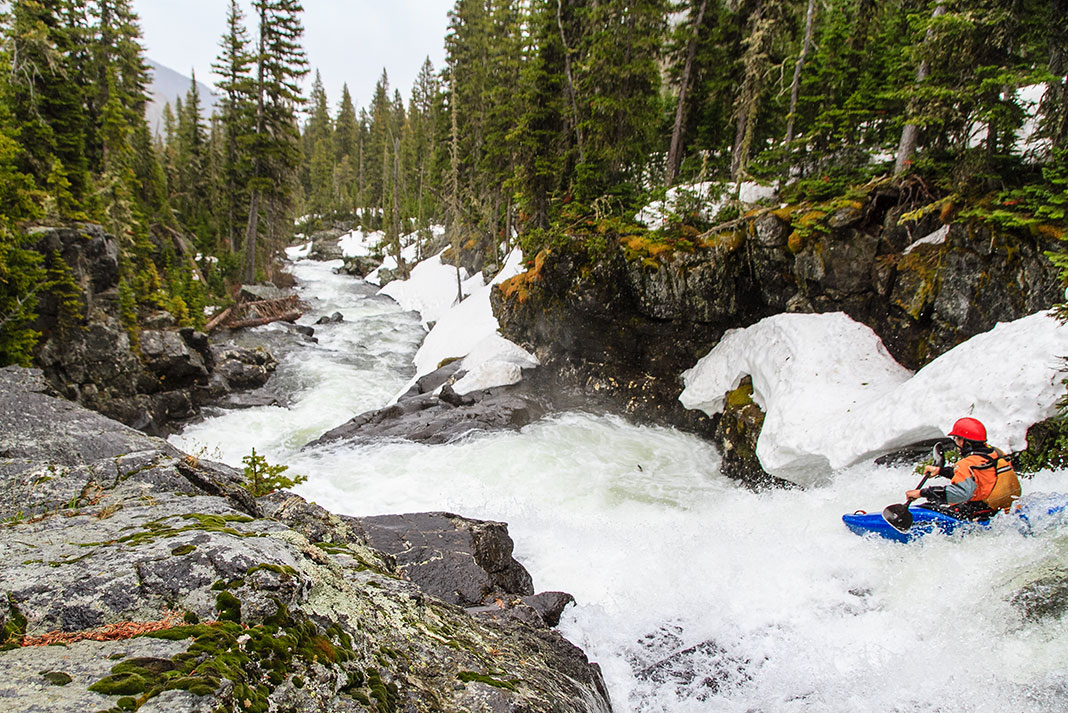 a whitewater paddler looks downriver during the spring runoff before running the scary rapids