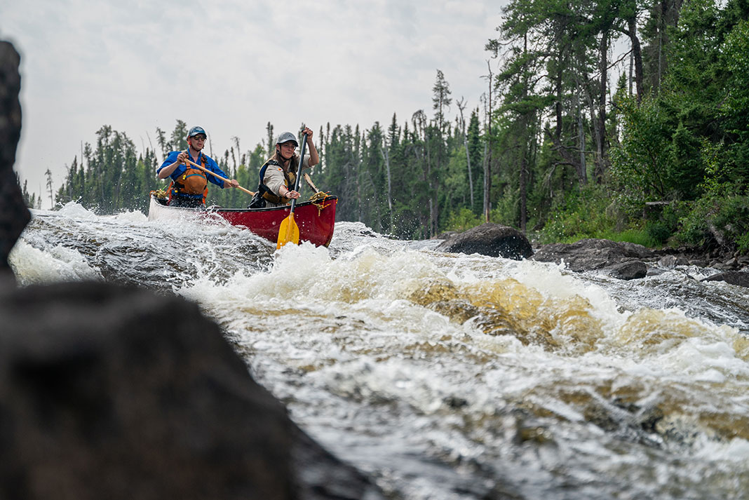 two people paddle a canoe through rapids on the Allan Water River