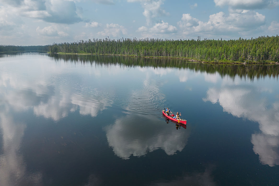 Canoeists paddle across glassy water on the Allan Water River
