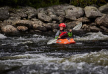 a young whitewater kayaker paddles on a rocky river