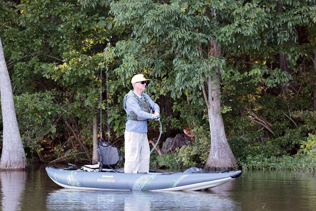 man stands and fishes from the Aquaglide Blackfoot Angler 130 inflatable kayak